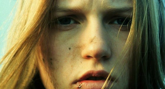 Frau mit langen blonden Haaren, die nach links blickt, vor hellem Hintergrund