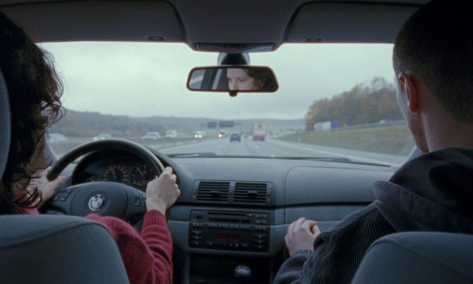 Blick von der Rückbank eines Autos auf die Fahrerin und den Beifahrer