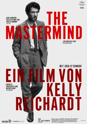 Filmplakat zu 'The Mastermind' : Mann in Anzug mit Krawatte und Händen in den Taschen, roter Text 'THE MASTERMIND EIN FILM VON KELLY REICHARDT' auf grauem Hintergrund.