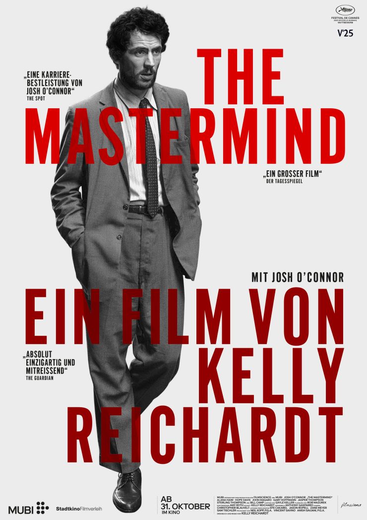 Filmplakat zu 'The Mastermind' : Mann in Anzug mit Krawatte und Händen in den Taschen, roter Text 'THE MASTERMIND EIN FILM VON KELLY REICHARDT' auf grauem Hintergrund.