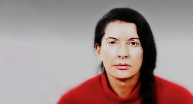 Marina Abramović mit rotem Pullover blickt in die Kamera.