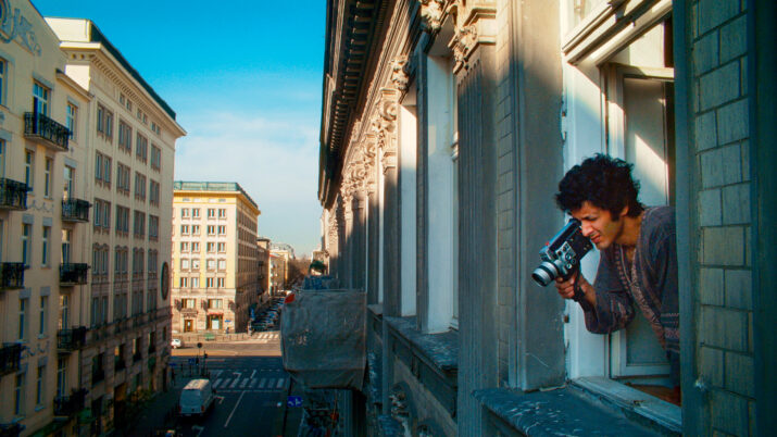Person lehnt aus einem Fenster eines historischen Gebäudes und hält eine Kamera in der Hand