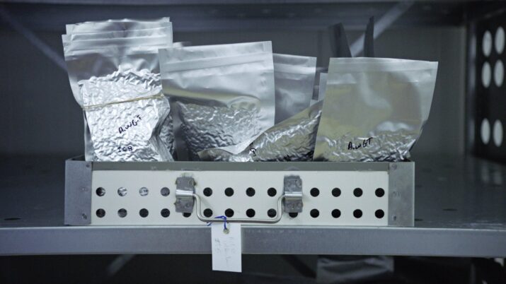 Metallbox mit mehreren silbernen, versiegelten Folienbeuteln, einige mit handschriftlichen Beschriftungen