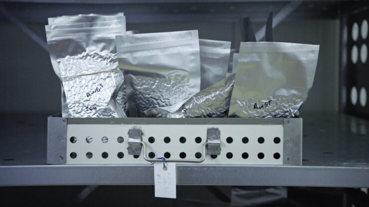 Metallbox mit mehreren silbernen, versiegelten Folienbeuteln, einige mit handschriftlichen Beschriftungen
