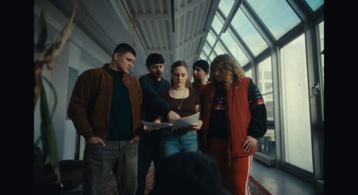 Fünf Jugendliche stehen im Halbreis und blicken gemeinsam auf einen Zettel.