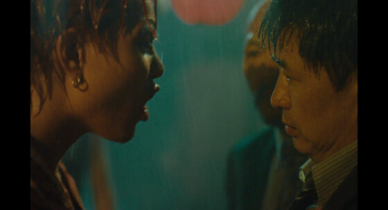 Porträt einer Frau mit kurzen Haaren und Ohrringen, die einem Mann mit verschwommenem Gesicht nahe gegenübersteht