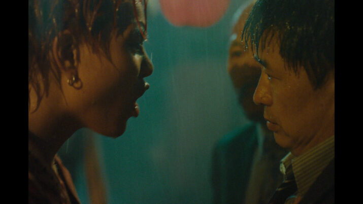 Porträt einer Frau mit kurzen Haaren und Ohrringen, die einem Mann mit verschwommenem Gesicht nahe gegenübersteht